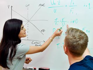 two students working on a white board